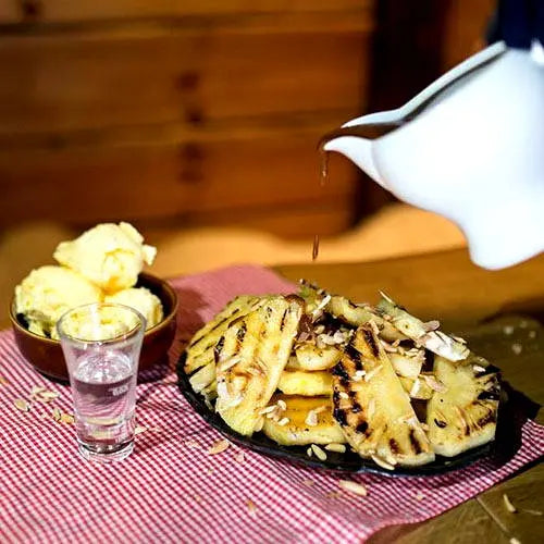 Gegrillte ananas mit karamellsauce, eiscreme und gerösteten mandeln - Campingaz & Coleman